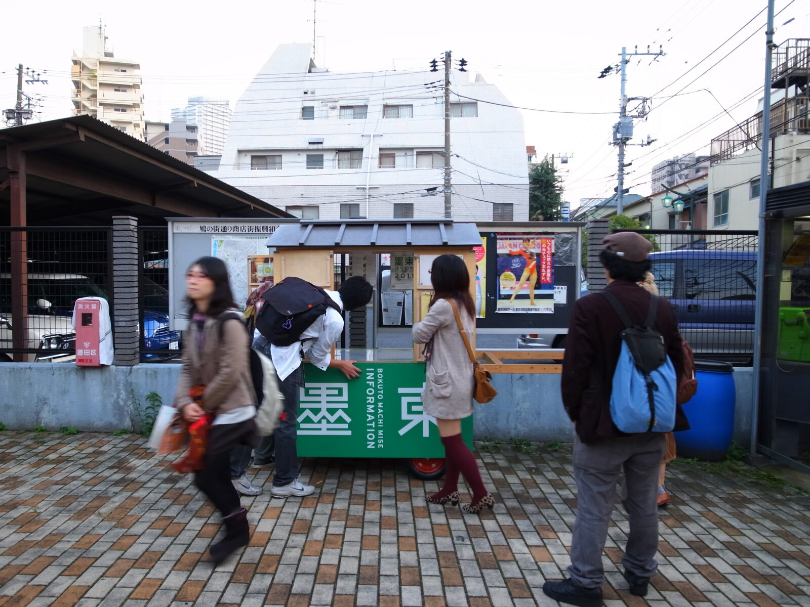 墨東と書かれた小さな屋台が道に置かれて、その前を人が歩いていたり、立ち止まったりしている