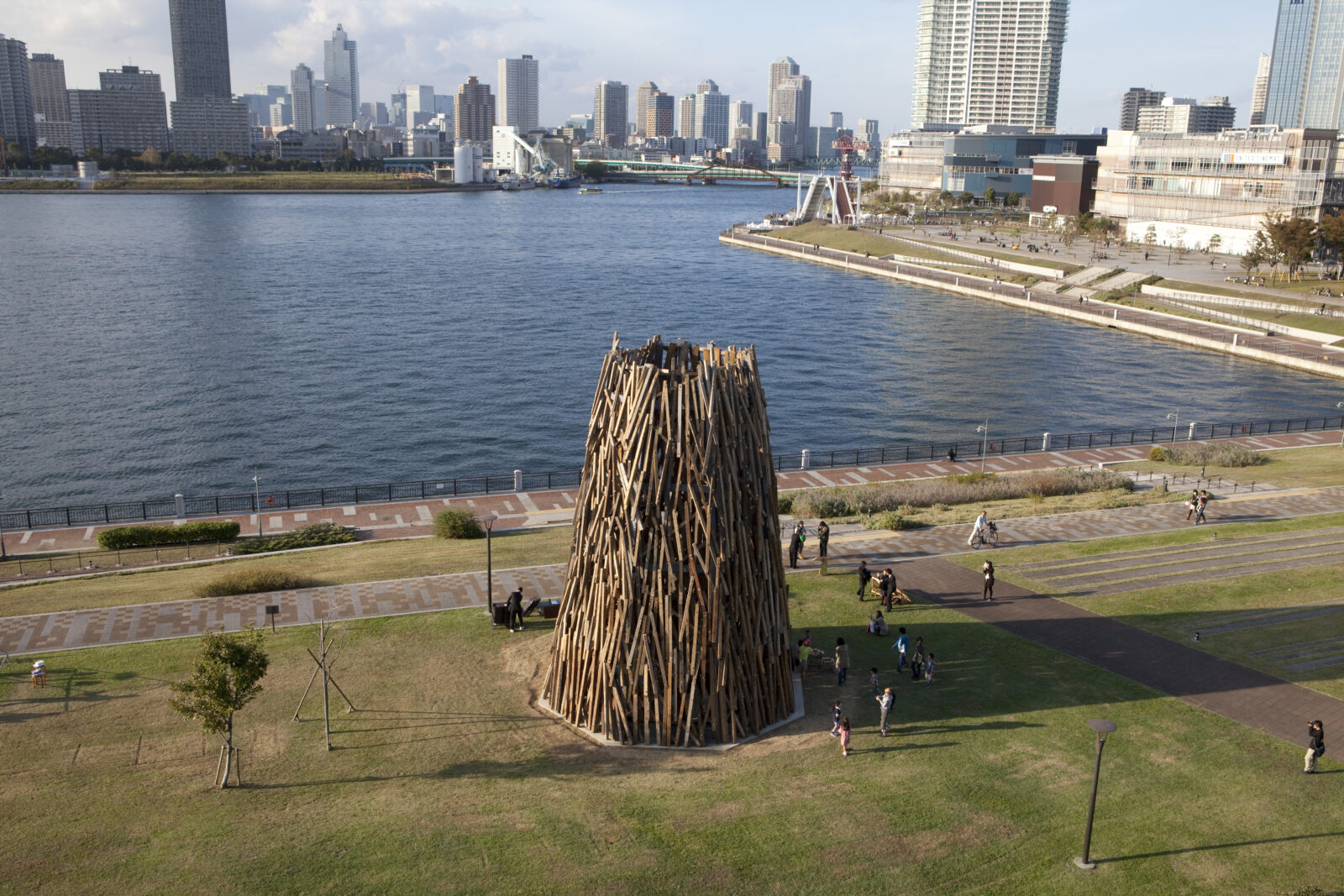 水辺のそばの広場に大きなタワー型のアート作品が建っている