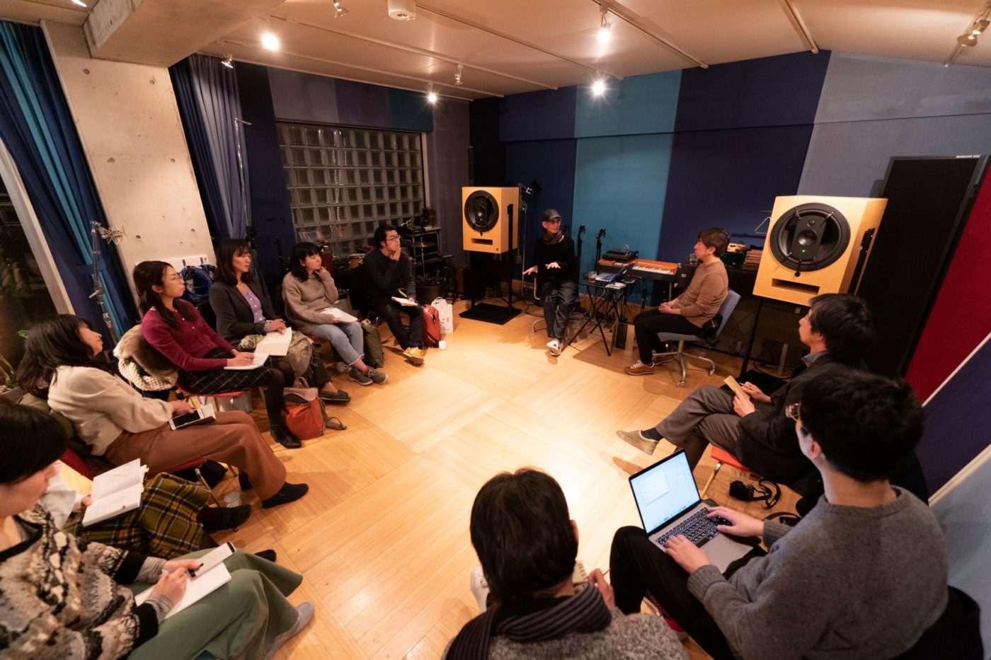 音楽スタジオのなかでのトークイベントの様子。10名ほどが椅子に座って、メモを取りながら話を聞いている
