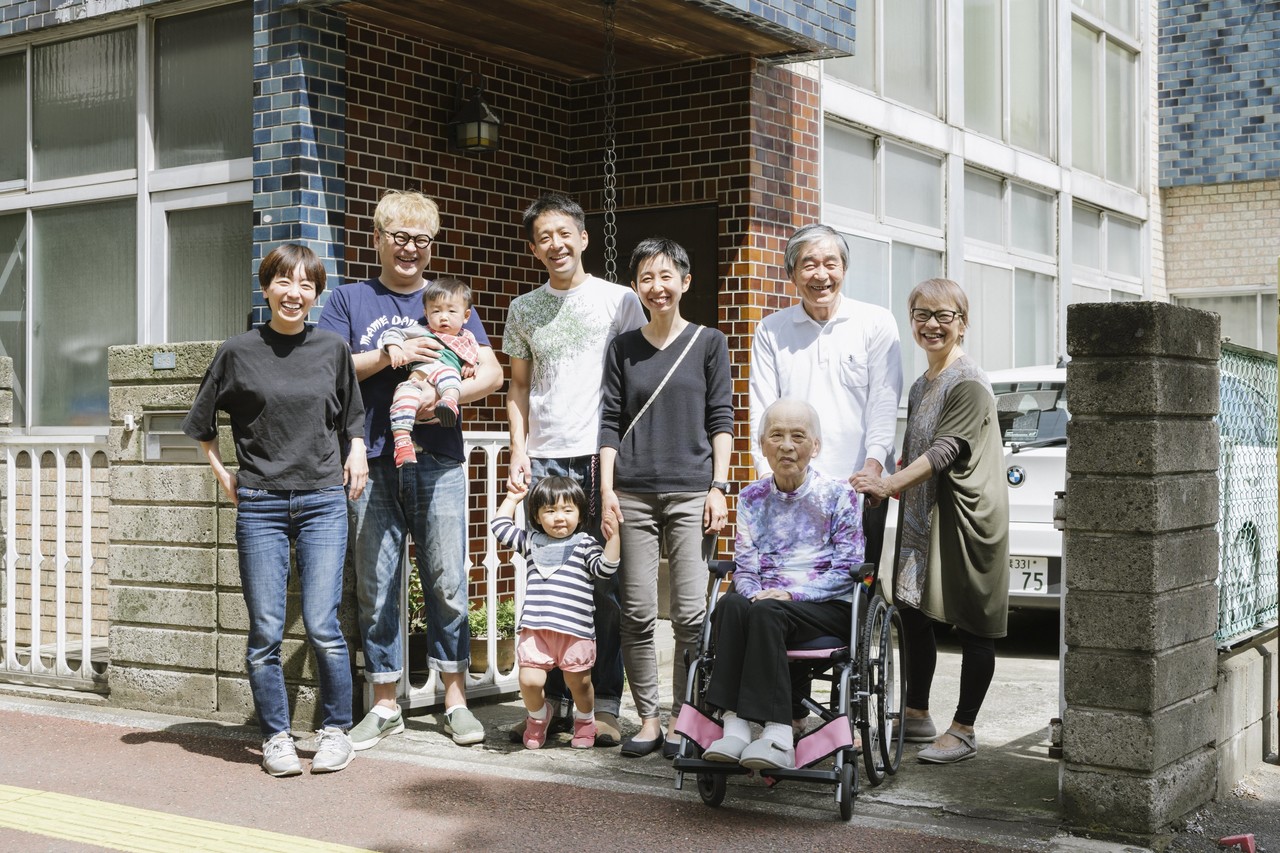 岩沢兄弟の一家の記念写真。4世代9人が家の前に集まっている