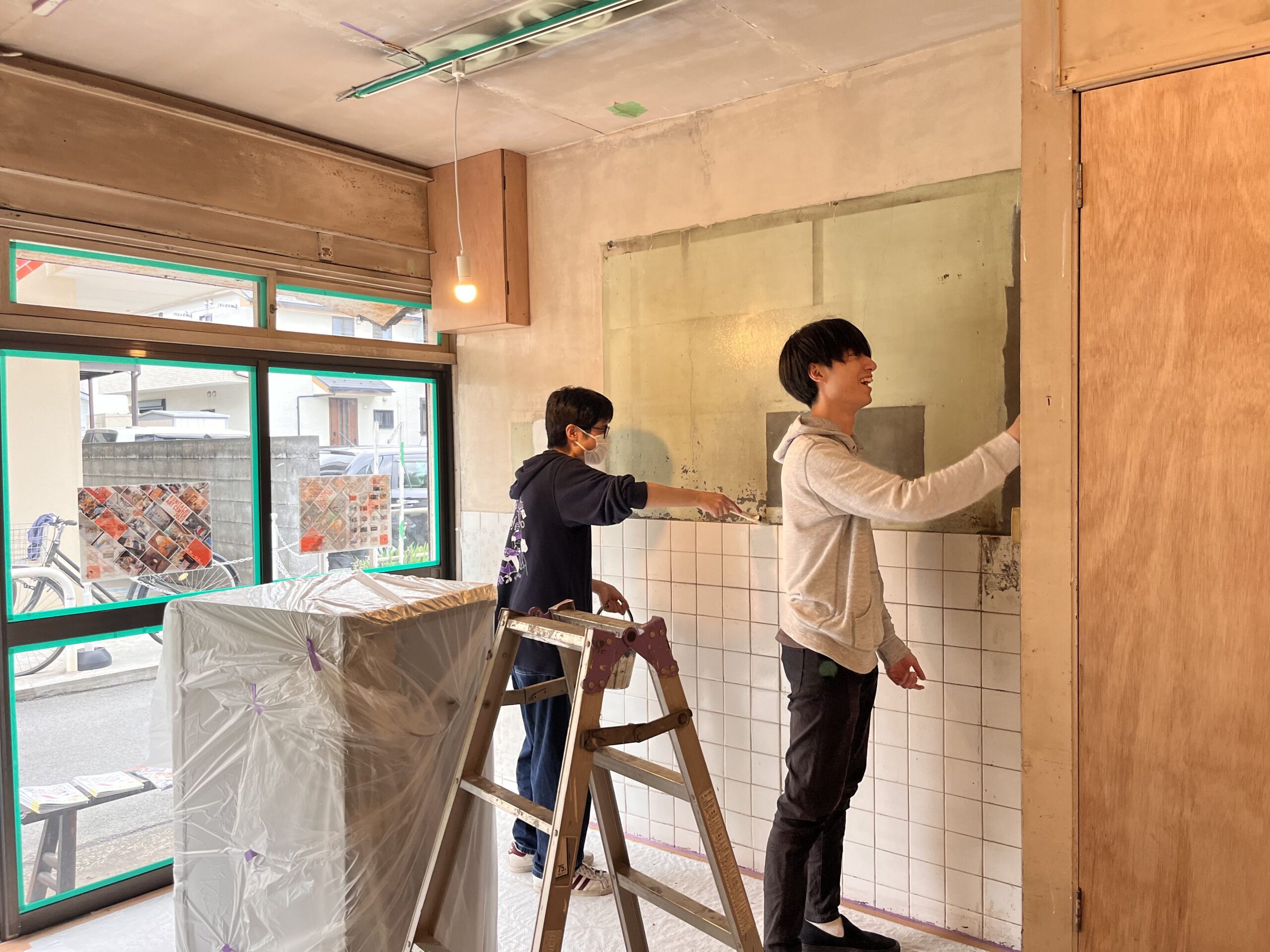 活動拠点「さえき洋品てん」をリノベーションしている様子。2人の参加者が部屋の壁に塗料を塗っている